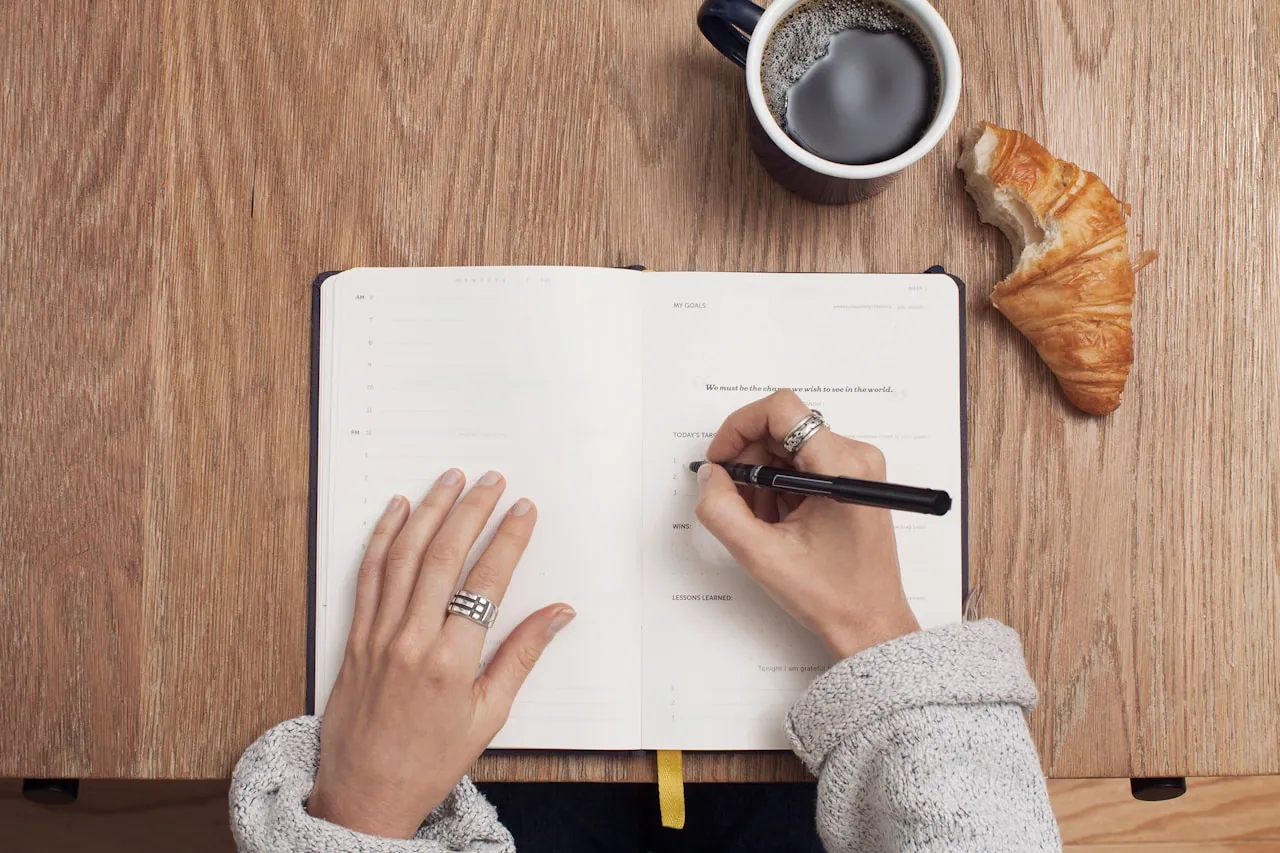 Woman writing intentions in a journal by soft morning light